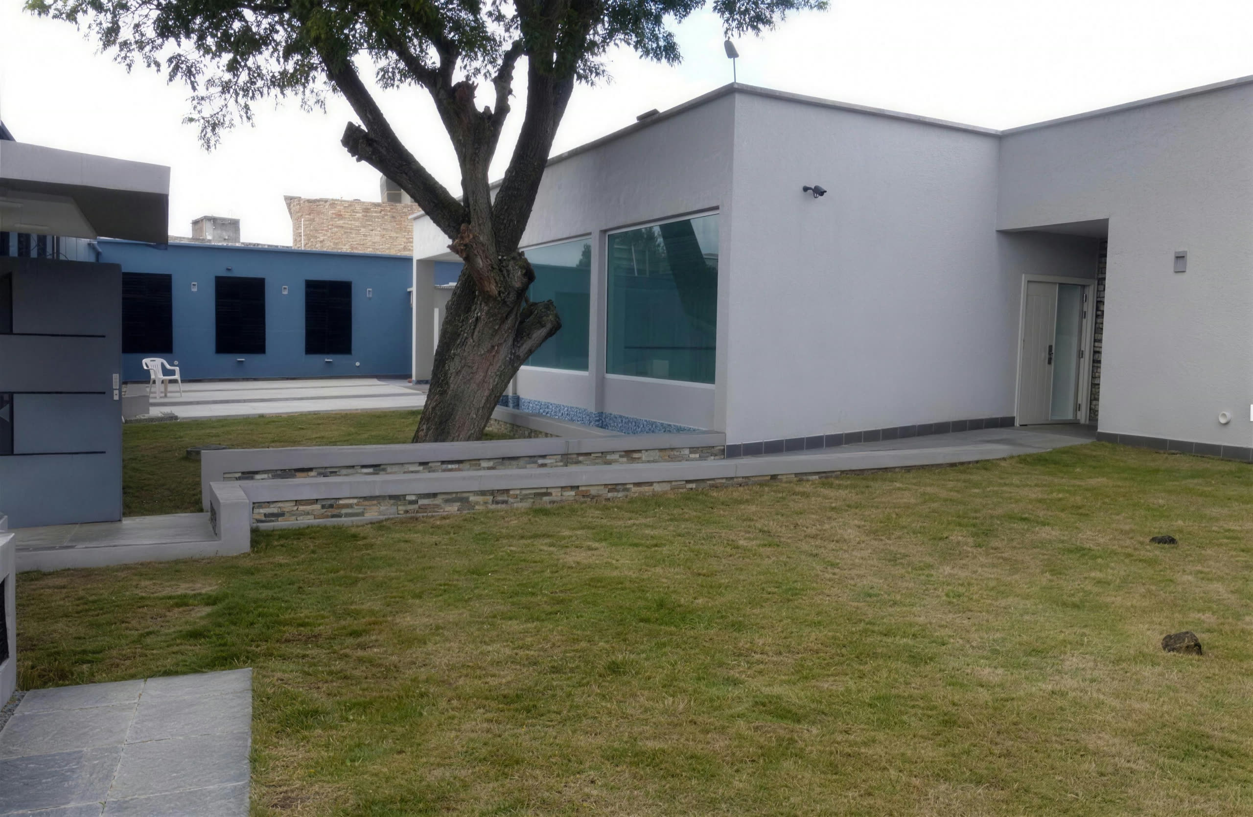 Fachada blanca con ventanal panorámico frente al jardín