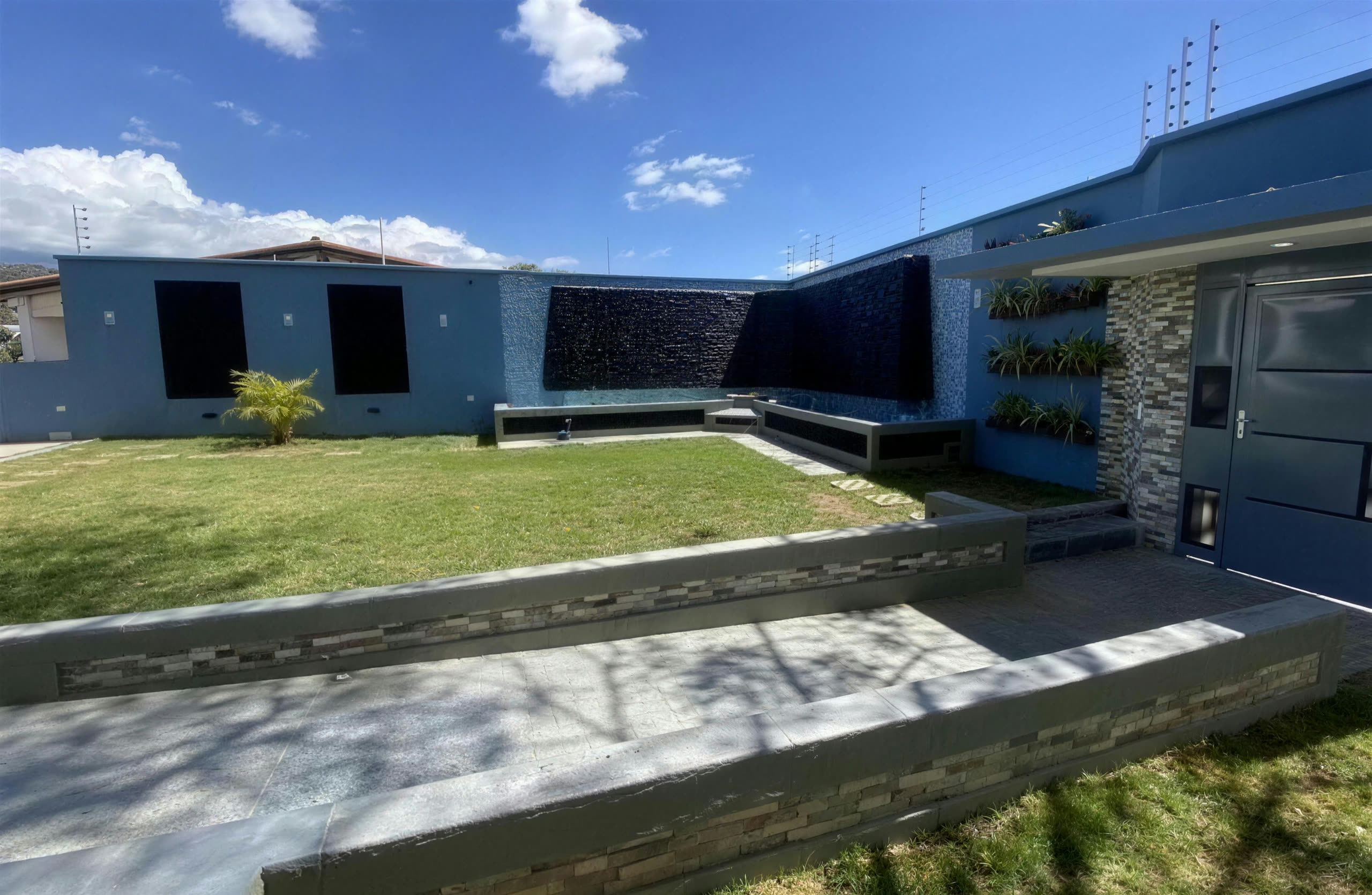 Entrada principal con jardineras verticales y piedra