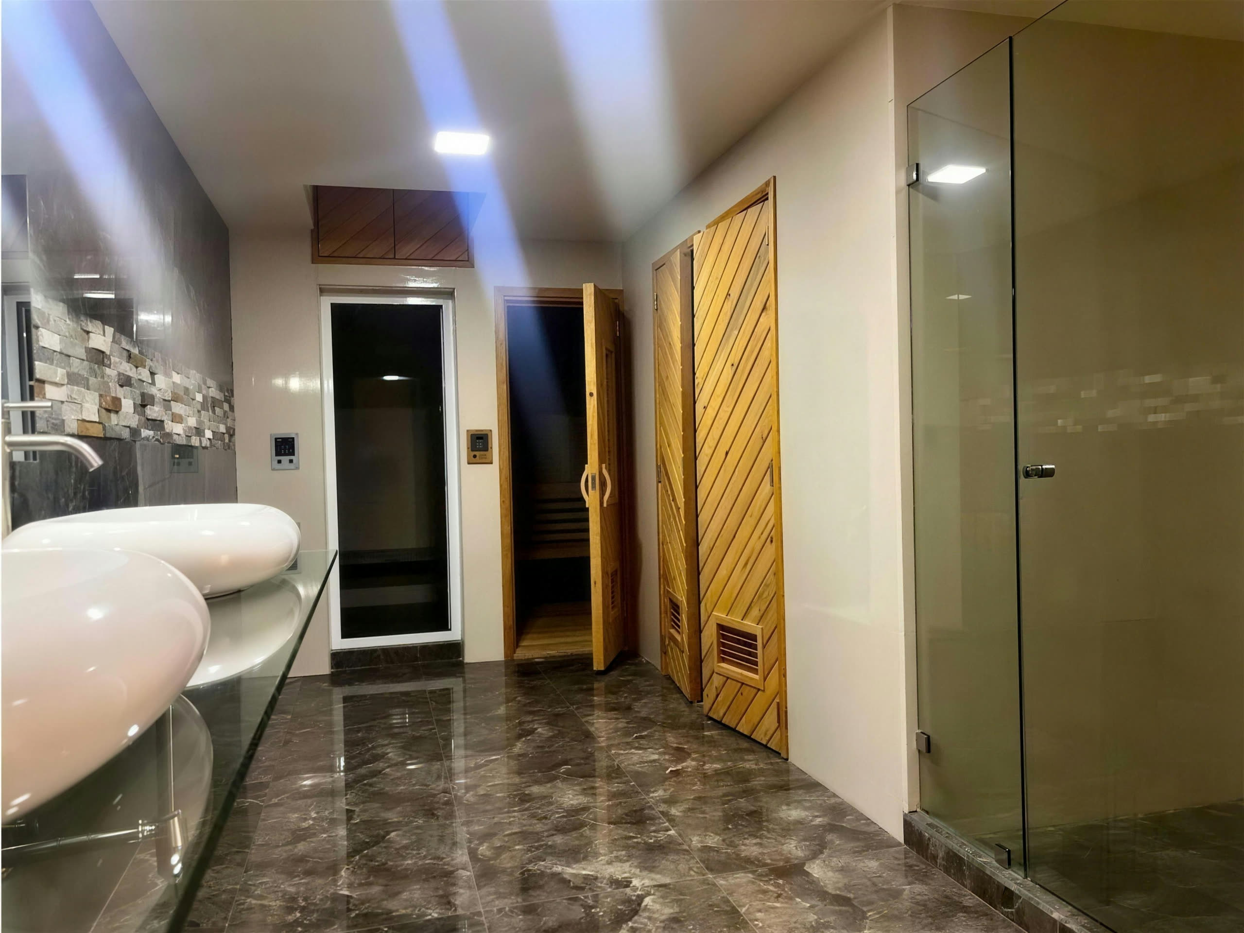 Antesala del spa con lavamanos negro y puertas de madera